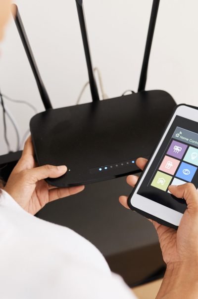 Hands of woman connecting smart home application on her phone to wi-fi router